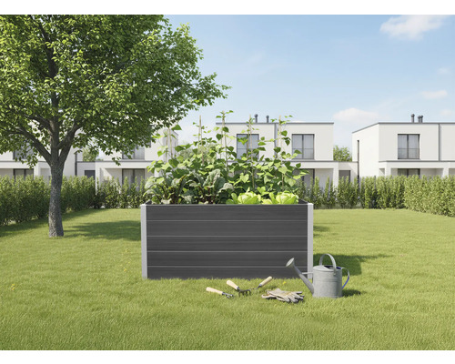 Hochbeet im Garten mit Gemüse, Gartengeräten und Gießkanne