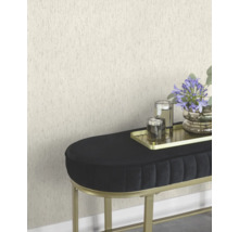 Scène avec un papier peint texturé, un banc noir avec un cadre doré, un plateau doré avec des bougies et un vase de fleurs.