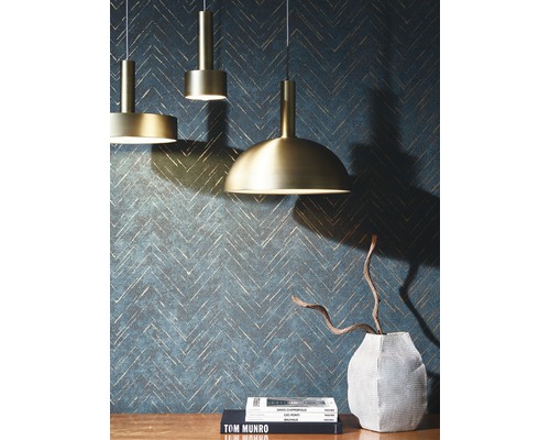 Trois suspensions dorées devant un mur à motif en zigzag