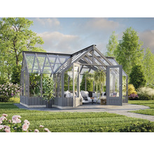 Serre avec murs en verre et portes doubles dans un jardin avec plantes et pelouse.