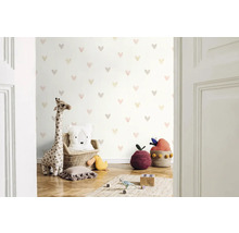 Chambre d'enfant avec papier peint à motifs de cœurs, peluche girafe et coussins décoratifs
