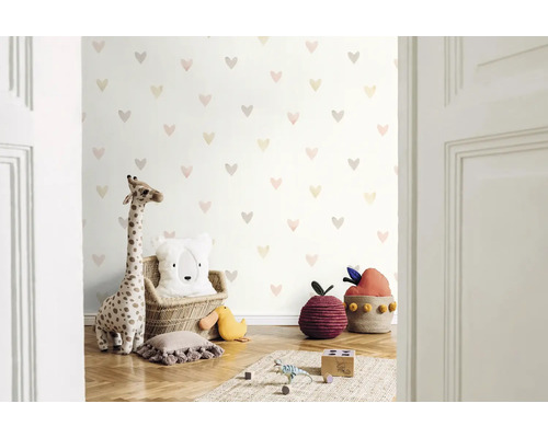 Chambre d'enfant avec papier peint à motifs de cœurs, peluche girafe et coussins décoratifs