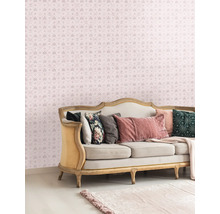 Salon décoratif avec un canapé et un papier peint à motifs avec des couronnes et des lettres.