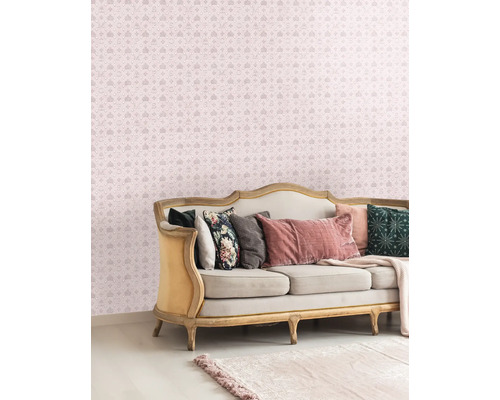 Salon décoratif avec un canapé et un papier peint à motifs avec des couronnes et des lettres.
