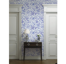 Vue d'une pièce avec du papier peint à motifs bleus et blancs, une commode, une lampe et des encadrements de porte