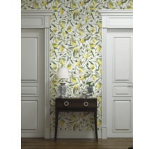 Vue d'une pièce avec papier peint à motifs de citrons et d'olives, commode, lampe et portes blanches.