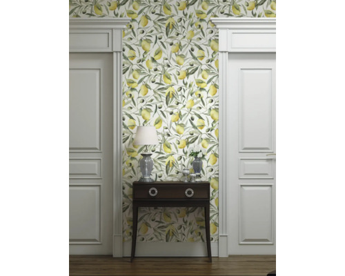 Vue d'une pièce avec papier peint à motifs de citrons et d'olives, commode, lampe et portes blanches.
