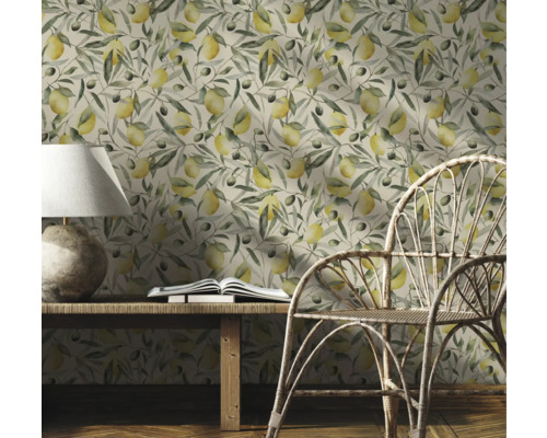 Pièce décorative avec un papier peint à motifs de citrons et de branches d'olivier, une table en bois, une lampe, un livre et une chaise en rotin.