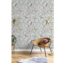 Pièce décorative avec papier peint à motifs d'oiseaux, fauteuil, lampadaire, miroir, plante d'intérieur et tapis