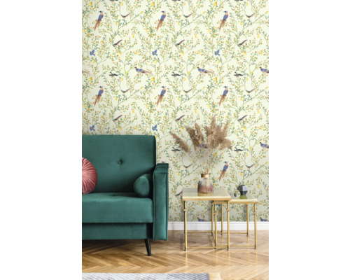 Vue d'une pièce avec un canapé en velours vert, une table d'appoint dorée et un papier peint à motif d'oiseaux