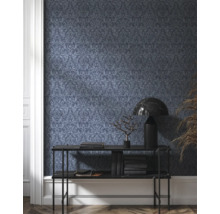 Vue d'une pièce avec papier peint à motifs sombres, console, lampe et décoration