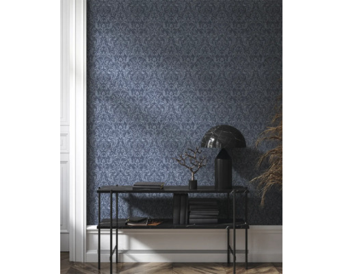 Vue d'une pièce avec papier peint à motifs sombres, console, lampe et décoration
