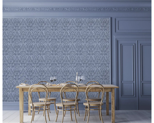 Salle à manger avec papier peint orné, table en bois et chaises.