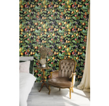 Chambre à coucher avec lit, fauteuil et revêtement mural à motifs de fruits.