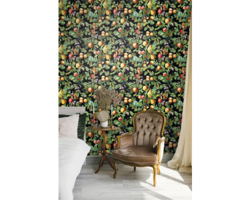 Chambre à coucher avec lit, fauteuil et revêtement mural à motifs de fruits.