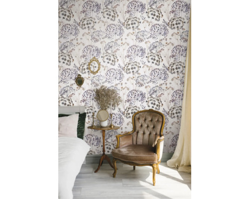 Chambre décorée avec lit, fauteuil, table d'appoint et papier peint fleuri