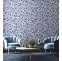 Salon avec papier peint à motifs floraux, deux fauteuils, une table basse et une table d'appoint.