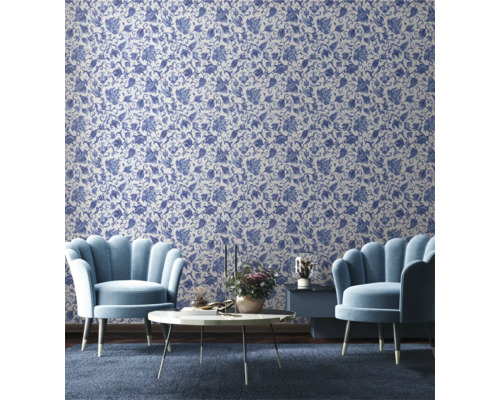 Salon avec papier peint à motifs floraux, deux fauteuils, une table basse et une table d'appoint.