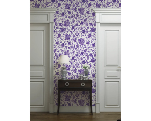 Vue d'une pièce avec papier peint à motifs floraux, commode et cadre de porte