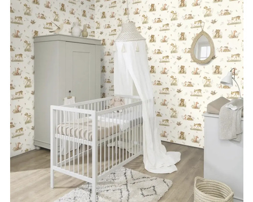Chambre d'enfant avec lit à barreaux, commode à langer et armoire devant un papier peint à motifs d'animaux.