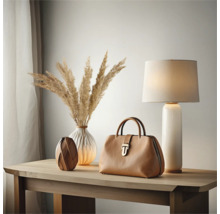 Scène décorative avec sac, lampe et vases sur une table en bois.