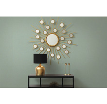 Intérieur décoratif avec miroir en forme de soleil, lampe et chandeliers sur une étagère.