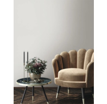 Scène décorative avec fauteuil, table d'appoint, chandeliers et vase de fleurs dans une ambiance élégante.