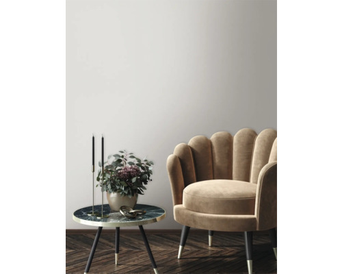 Scène décorative avec fauteuil, table d'appoint, chandeliers et vase de fleurs dans une ambiance élégante.