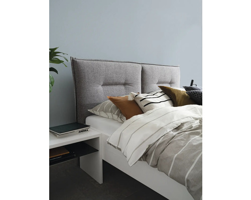Chambre avec lit, tête de lit rembourrée, coussins et table de chevet