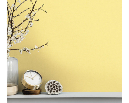 Scène décorative avec horloge, vase et décoration végétale devant un mur