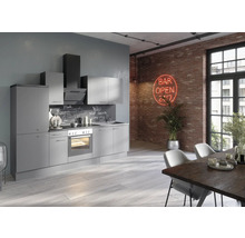 Cuisine moderne avec armoires grises, four et hotte aspirante devant un mur de briques avec enseigne lumineuse