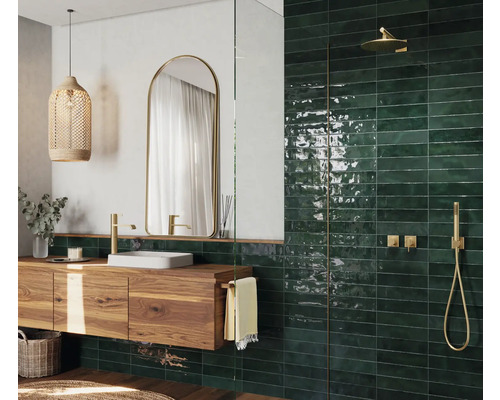 Modernes Badezimmer mit Holzwaschtisch, Spiegel, Hängeleuchte und grünen Fliesen im Duschbereich