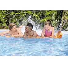 Trois enfants jouent dans la piscine avec des éclaboussures d'eau