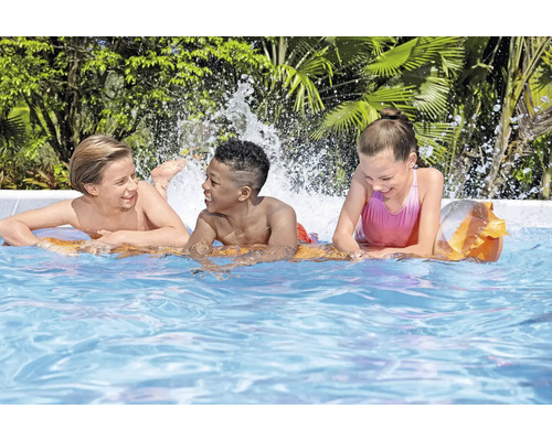 Trois enfants jouent dans la piscine avec des éclaboussures d'eau