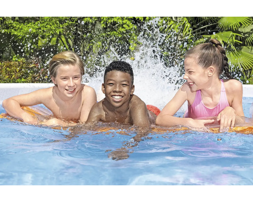 Trois enfants sourient dans une piscine sur un matelas pneumatique.