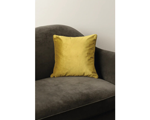 Coussin décoratif jaune en velours sur un fauteuil