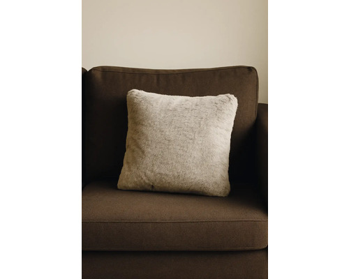 Coussin décoratif carré aspect fourrure sur canapé marron