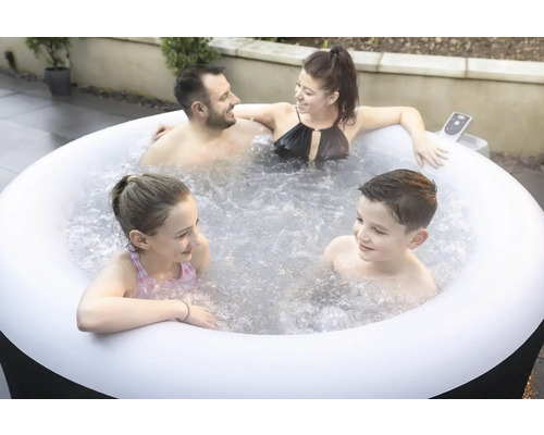 Une famille se détend dans un jacuzzi gonflable dans le jardin.