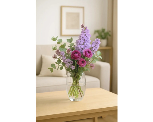 Arrangement floral composé de lilas mauve et de roses dans un vase en verre sur une table