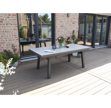 Scène de jardin avec une table à manger en béton et métal sur une terrasse