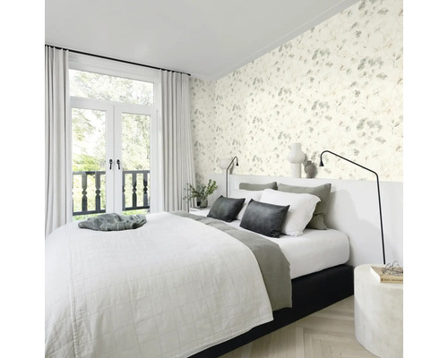 Schlafzimmer mit floraler Tapete, Bett und Fenstertüren zum Balkon.