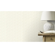 Gros plan d'un mur avec un papier peint à motif floral, à côté d'une lampe sur une table en bois