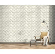 Salon avec papier peint géométrique, fauteuil et lampadaire.