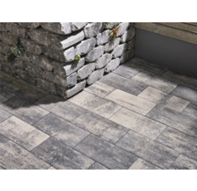 Graue Pflastersteine und eine Mauer aus Steinblöcken im Aussenbereich.