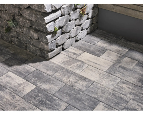 Graue Pflastersteine und eine Mauer aus Steinblöcken im Aussenbereich.