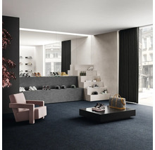 Salle de vente avec chaussures sur marches d'escalier et podiums, fauteuil et moquette