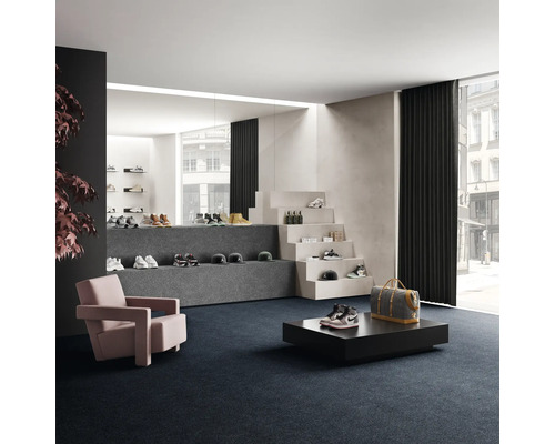 Salle de vente avec chaussures sur marches d'escalier et podiums, fauteuil et moquette