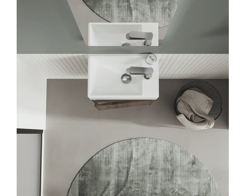 Aufsicht eines Badezimmers mit Waschbecken, Armatur, Spiegel, rundem Teppich und Wäschekorb