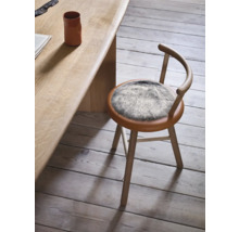 Chaise en bois avec assise ronde et revêtement en fourrure à côté d'une table en bois