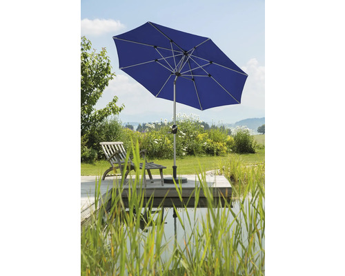 Blauer Gartenschirm neben einem Teich und einer Holzterrasse mit Liegestuhl